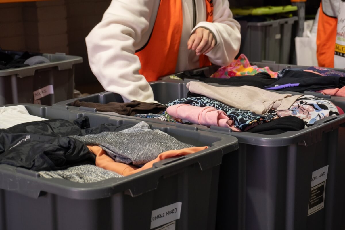 Volunteer sorts through bins filled with folded clothes